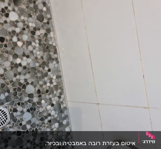 אזור מקלחון בחדר רטוב עם רצפת חלוקי נחל וקיר קרמיקה